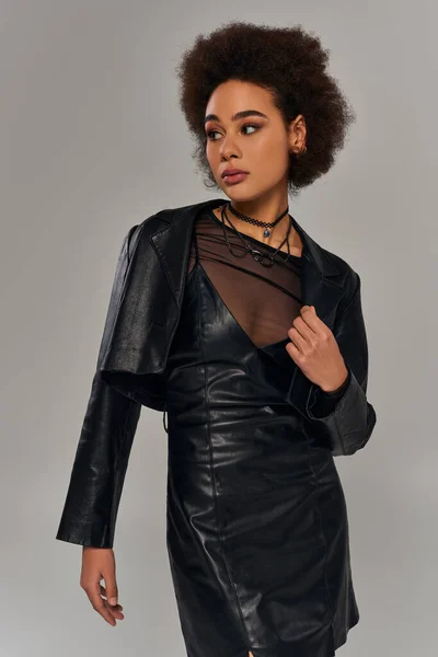 Schöne trendige afrikanisch-amerikanische Model in stilvoller schwarzer Kleidung posiert auf grauem Hintergrund — Stockfoto