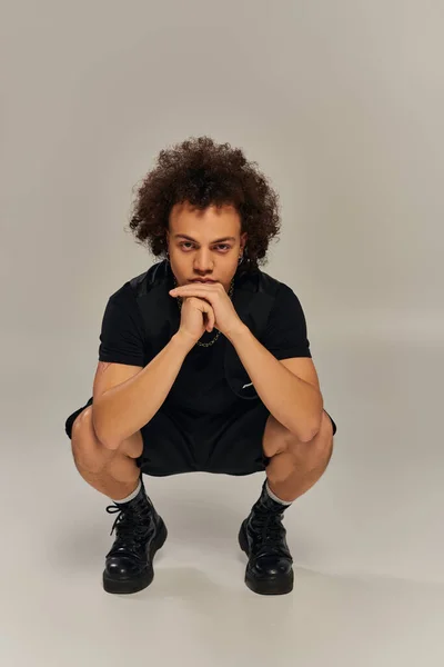Bonito afro americano masculino modelo no preto urbano elegante traje posando ativamente no fundo cinza — Fotografia de Stock