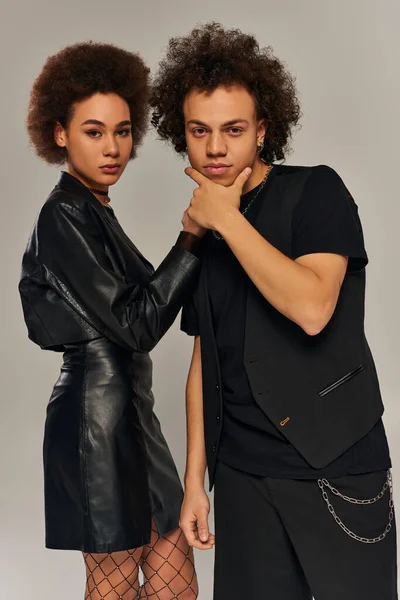 Stylish african american brother and sister in black clothes posing together on gray backdrop — Stock Photo