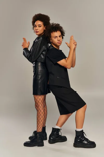 Trendy africano americano fratello e sorella in abiti neri in posa insieme su sfondo grigio — Foto stock