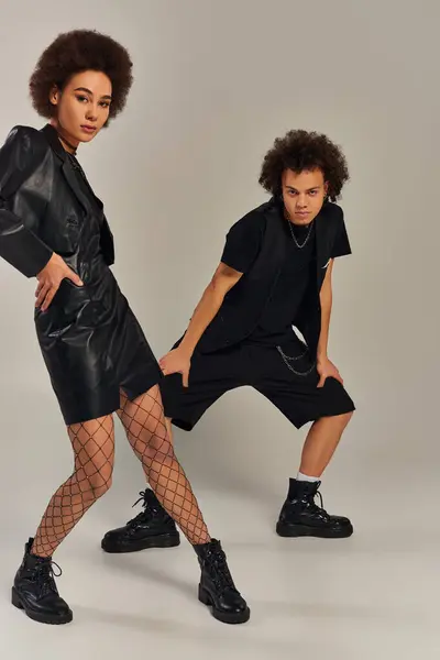 Young african american brother and sister in black outfit posing together on gray backdrop, family — Stock Photo