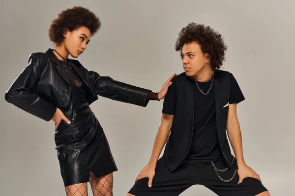 Стильный африканский американский брат и сестра в модном черном наряде позируют вместе на сером фоне — стоковое фото