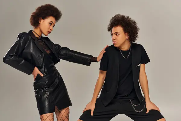 Stylish african american brother and sister in trendy black outfit posing together on gray backdrop — Stock Photo