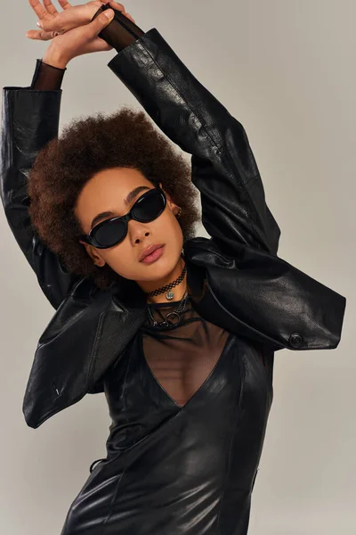 Portrait of fashionable african american woman in sunglasses and stylish outfit on gray backdrop — Stock Photo