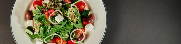 Фото тарелки со свежеприготовленным вкусным греческим салатом на сером фоне, баннер — стоковое фото