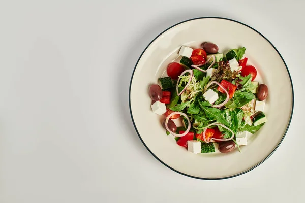 Foto vista superior da placa com salada grega tradicional recém-feita em fundo cinza, alimentação saudável — Fotografia de Stock