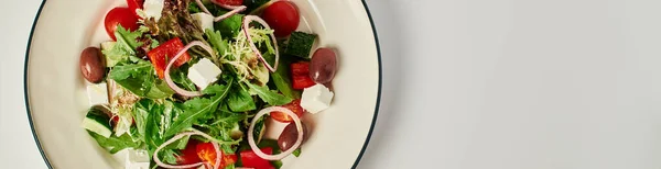Foto vista superior da placa com salada grega tradicional recém-feita no fundo cinza, banner de comida — Fotografia de Stock