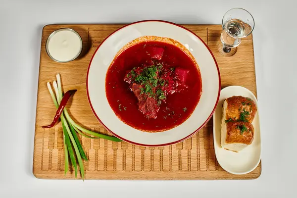 Traditionelle ukrainische Borschtsch-Suppe mit frischem Dill in der Nähe von Knoblauchbrötchen und saurer Sahne auf Schneidebrett — Stockfoto