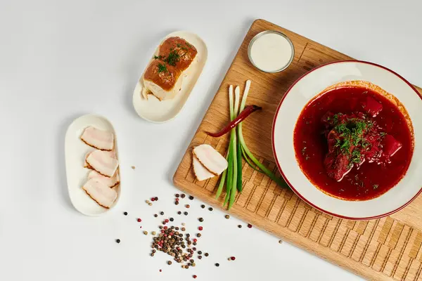 Traditional Ukrainian borsch near garlic buns, pork lard and green onions on wooden cutting board — Stock Photo