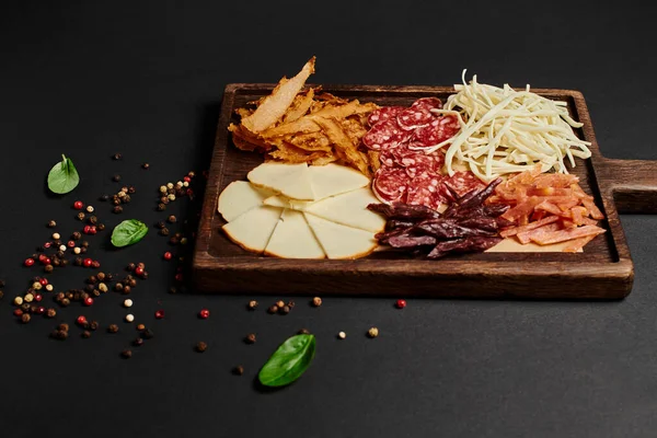 Top view of charcuterie board with cheese selection, dried beef and salami on black, antipasto — Stock Photo