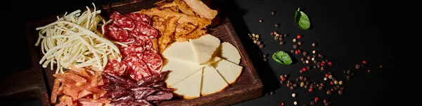 Banner de charcutaria com seleção de queijo gourmet, carne seca e fatias de salame em preto — Fotografia de Stock