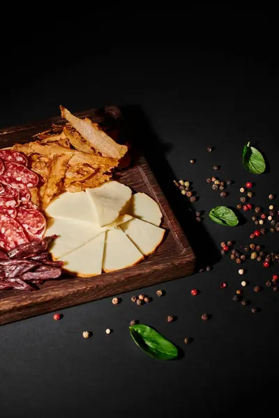 Saborosa placa de charcutaria com seleção de queijo gourmet, carne seca e salame em preto — Fotografia de Stock