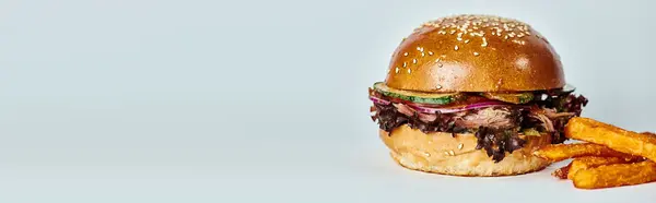 Pancarta de sabrosa hamburguesa con carne de res, cebolla roja, tomate y pan de sésamo cerca de papas fritas en gris - foto de stock