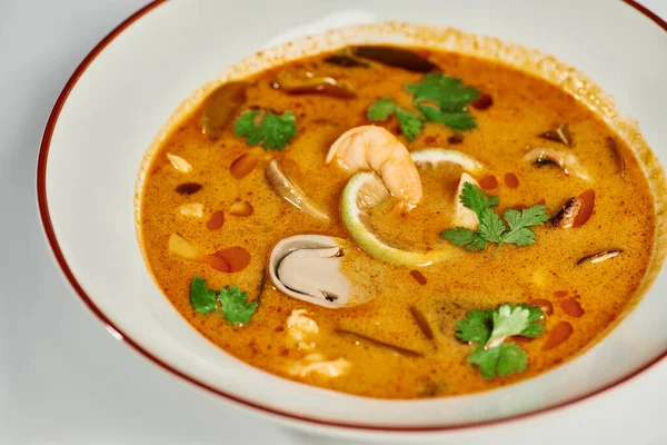 Spicy Thai soup with coconut milk, shrimp, lemongrass and cilantro on grey backdrop, Tom yum — Stock Photo