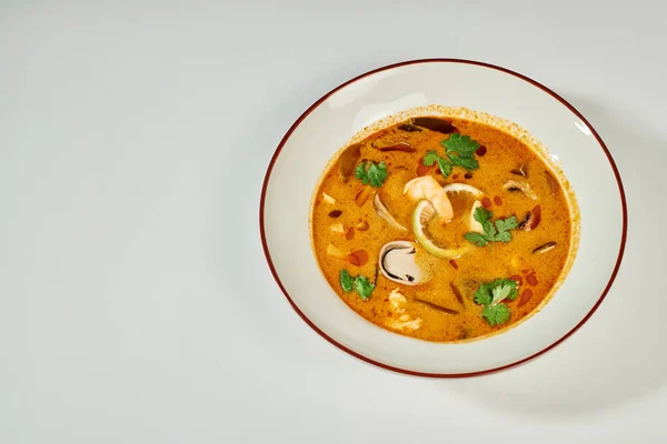 Soupe thaïlandaise crémeuse au lait de coco, crevettes, citronnelle et coriandre sur fond gris, Tom yum — Photo de stock