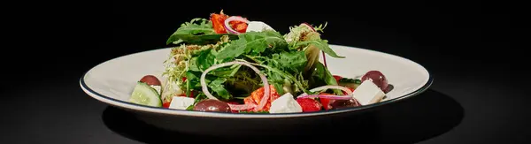 Pancarta de comida saludable, deliciosa ensalada griega con queso feta, cebolla roja, hojas de rúcula en negro - foto de stock