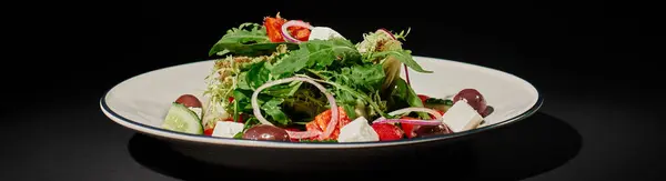 Healthy eating banner, delicious Greek salad with feta cheese, red onion, arugula leaves on black — Stock Photo