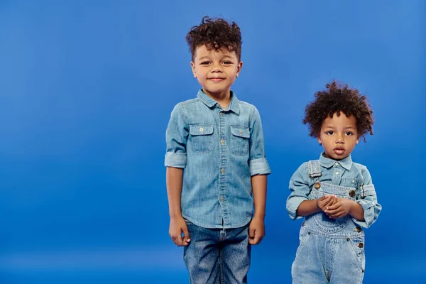 Heureux garçon préscolaire afro-américain en denim étreignant frère tout-petit sur bleu, bannière — Photo de stock