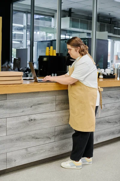 Jovem com síndrome de down usando laptop no balcão enquanto trabalhava no café moderno, inclusividade — Fotografia de Stock