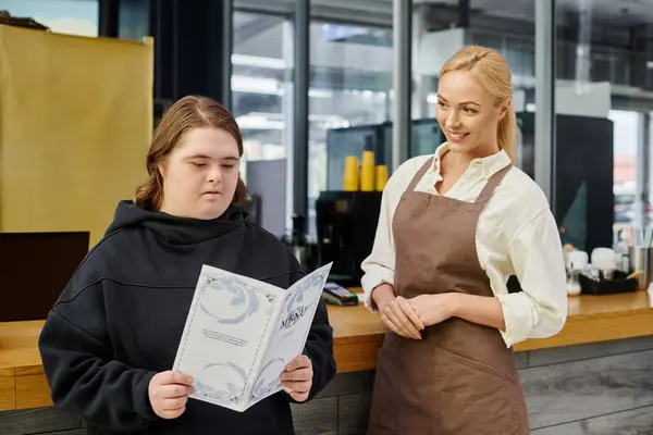 Young woman with mental disorder looking at menu card near smiling administrator in modern cafe — Stock Photo