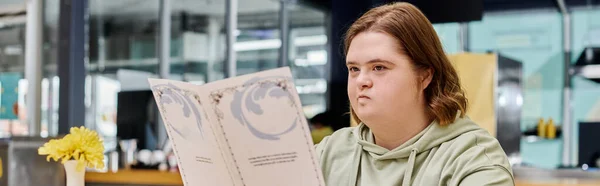 Young woman with down syndrome holding menu card and thinking in modern cafe, horizontal banner — Stock Photo