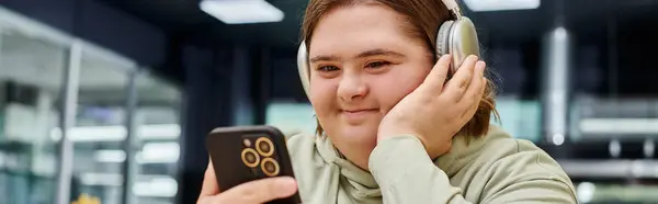 Happy woman with mental disorder listening music in headphone and holding smartphone in cafe, banner — Stock Photo