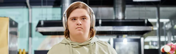 Young female customer with mental disability listening music in wireless headphones in cafe, banner — Stock Photo