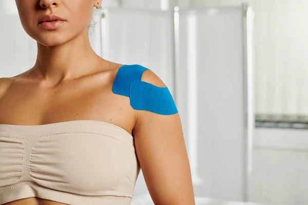 Good looking young woman with kinesiological tapes on her shoulder during appointment, healthcare — Stock Photo