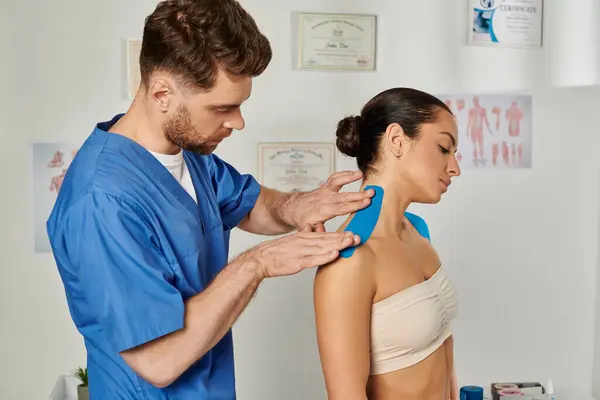 Красивий бородатий лікар кладе кінезіологічну стрічку на шию свого пацієнта, охорона здоров'я — стокове фото