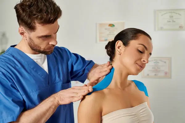 Handsome doctor putting kinesiological tape on neck of his patient during appointment, healthcare — Stock Photo