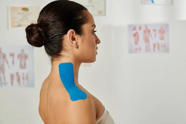 Beautiful young patient with kinesiological tapes on her body posing in profile, healthcare — Stock Photo