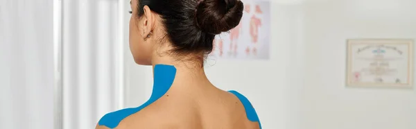 Вид ззаду молодої жінки-пацієнта зі стрічками кінезіо на шиї і плечах, охорона здоров'я, банер — стокове фото