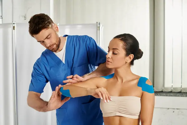 Mujer joven en cita con su médico que poner cintas de kinesio en su cuerpo, atención médica - foto de stock