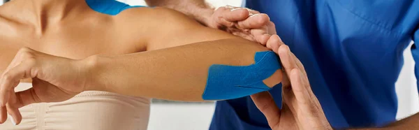Cropped view of doctor putting kinesiological tapes on elbow of young woman, healthcare, banner — Stock Photo