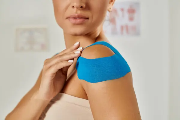 Jeune patiente avec des bandes kinésiologiques sur l'épaule pendant le rendez-vous, soins de santé — Photo de stock