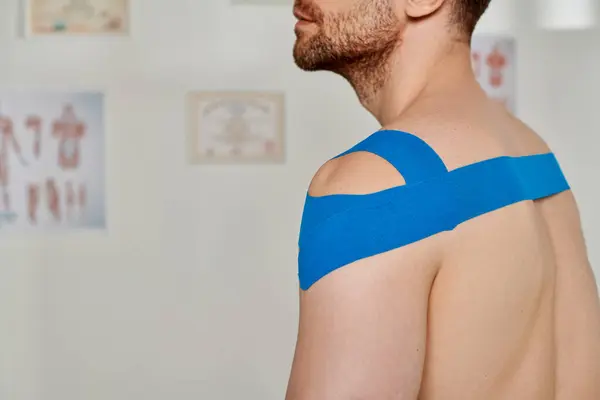 Cropped view of man with blue kinesiological tapes on shoulder during appointment, healthcare — Stock Photo