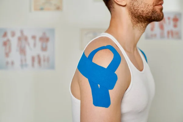 Visão cortada do homem com fitas cinesiológicas no ombro durante a consulta, cuidados de saúde — Fotografia de Stock