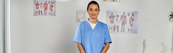 Joyous attractive young doctor in medical costume posing in her office and smiling at camera, banner — Stock Photo
