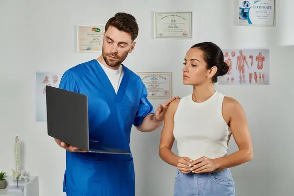 Bonito barbudo médico e seu jovem paciente olhando para laptop durante a consulta, cuidados de saúde — Fotografia de Stock