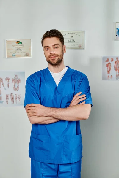 Beau médecin barbu avec les bras croisés sur la poitrine en regardant directement la caméra, les soins de santé — Photo de stock