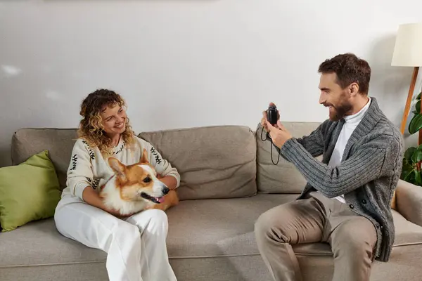Uomo sorridente e scattare foto di moglie con cane corgi sulla macchina fotografica in appartamento moderno, momenti felici — Foto stock