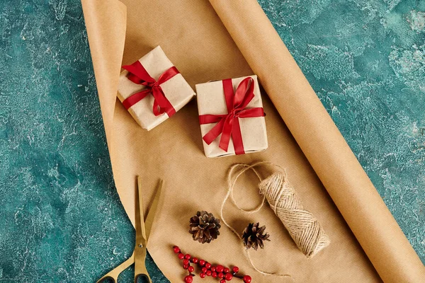 Coffrets cadeaux avec rubans près des cônes de pin et ciseaux avec ficelle sur papier artisanal, cadeaux bricolage — Photo de stock