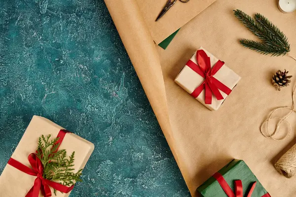 Fournitures de décoration bricolage près de boîtes-cadeaux avec des rubans rouges sur la surface texturée bleue, fond de Noël — Photo de stock