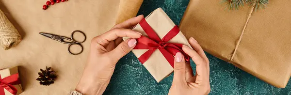Frau bindet rote Schleife auf Geschenk in der Nähe von Bastelpapier und Weihnachtsdekorationsartikeln, horizontales Banner — Stockfoto