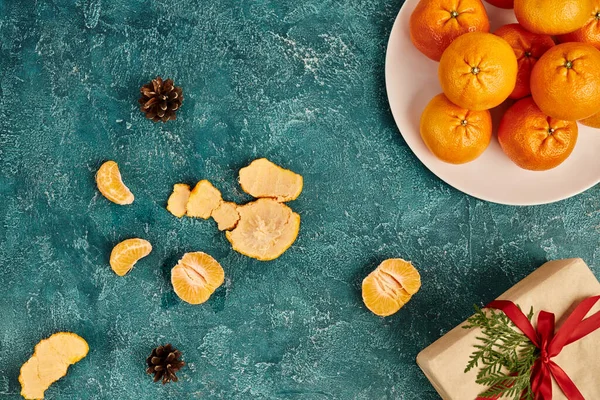 Caixa de presente decorado e tangerinas perto de cones de pinho em fundo texturizado azul, Natal ainda vida — Fotografia de Stock
