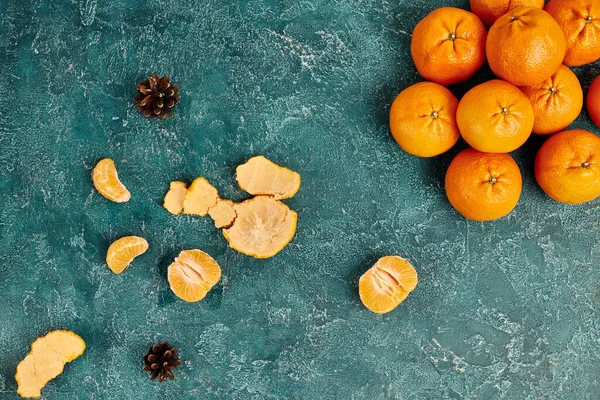 Vue de dessus des mandarines juteuses et des cônes de pin sur la surface rustique bleue, fond de Noël coloré — Photo de stock