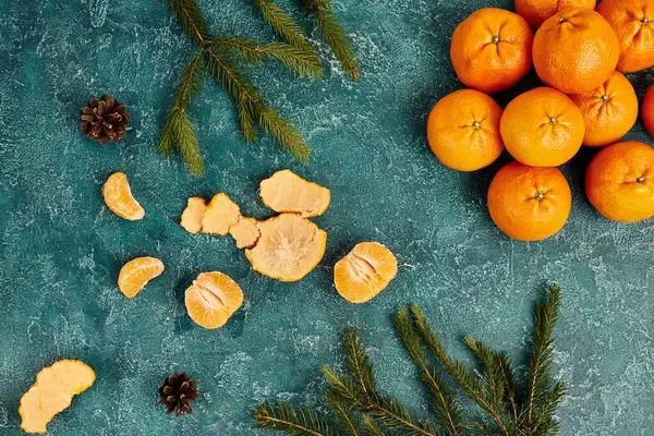 Fresh mandarins and pine cones with fir branches on blue rustic backdrop, Christmas theme, top view — Stock Photo