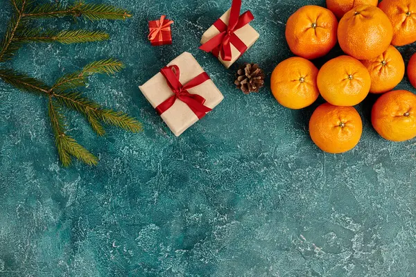 Mandarinen und verzierte Geschenkboxen in der Nähe von Kiefernzweigen auf blauem Hintergrund, Weihnachtsgegenstände — Stockfoto