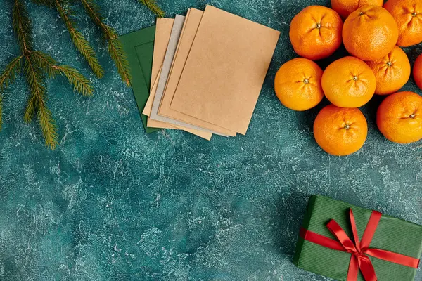 Tangerinas frescas e envelopes multicoloridos perto de ramos de pinho na textura azul, Natal ainda vida — Fotografia de Stock