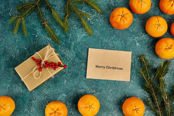 Enveloppe avec Joyeux Noël lettrage près de mandarines et boîte cadeau avec des baies de houx, Noël — Photo de stock